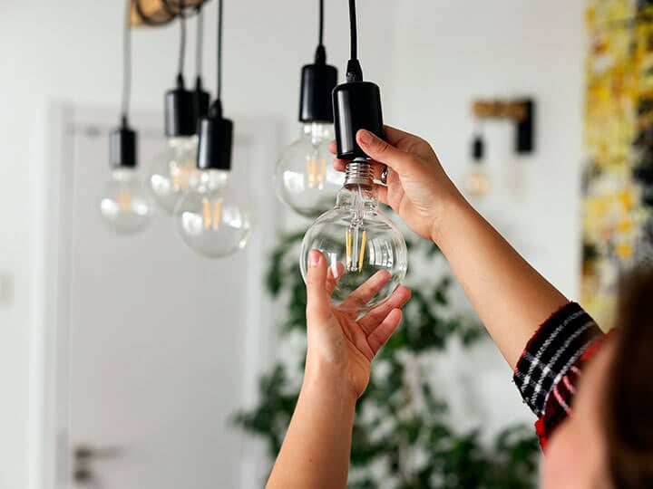 Close-up view of a Caucasian female changing a light bulb to an LED bulb