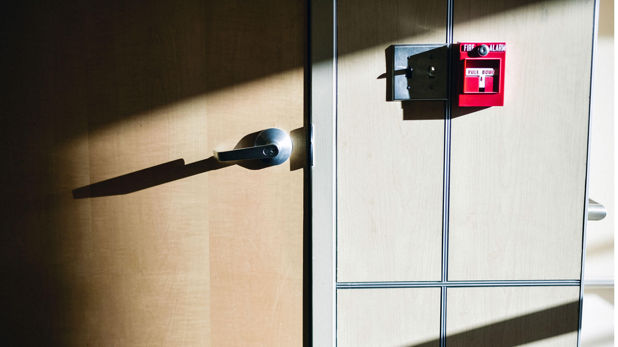 Commercial building door with fire alarm on the side beautifully lit by sunbeam