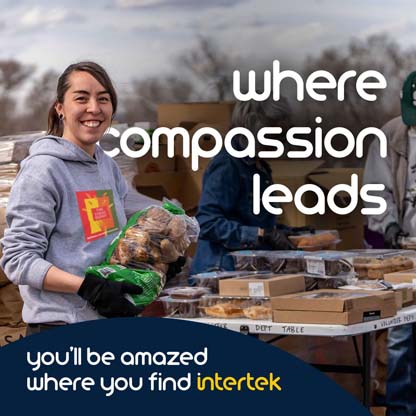 A woman smiling while carrying a sack of potatoes next to a table full of food